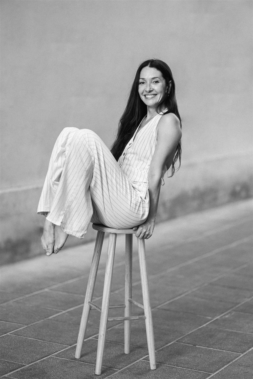 Aida sentada en un taburete, sonriendo