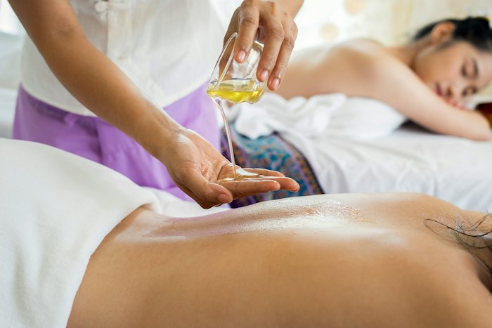 Aceite templado vertido sobre la espalda durante un masaje